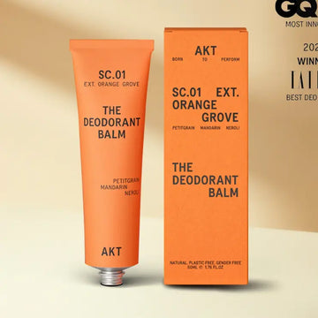 Orange deodorant balm tube and packaging on a beige background
