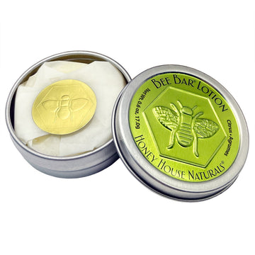 Bee bar lotion in a metal tin with a green label featuring a bee design, from Honey House Naturals.