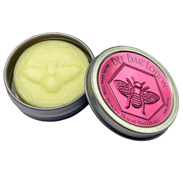 Bee bar lotion in a metal tin with a pink label featuring a bee design.