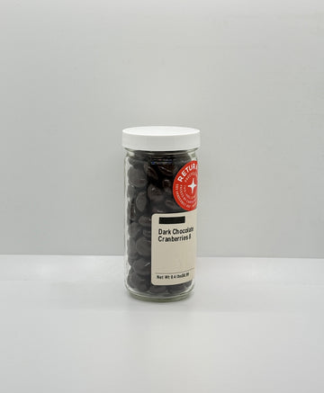 Jar of dark chocolate cranberries with a white lid on a gray background