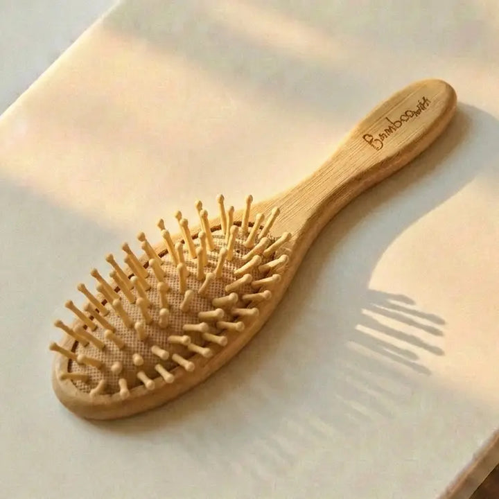 Wooden hairbrush on a light surface with 'Bamboo' branding.