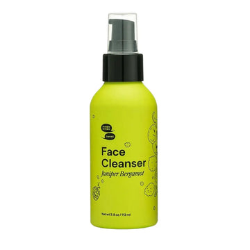 Green bottle of face cleanser with black spray nozzle on a white background