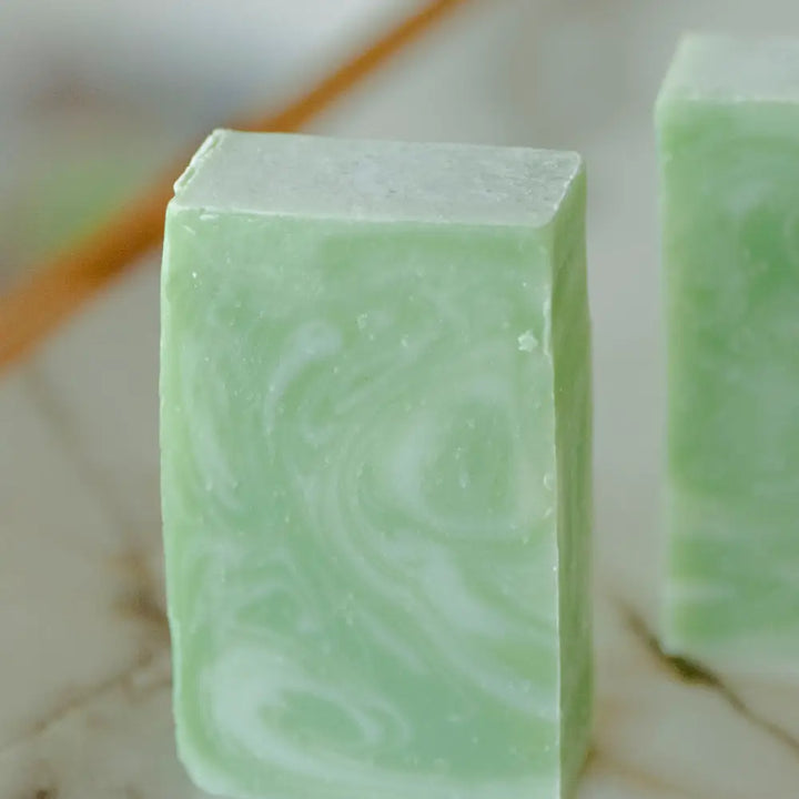 Green soap bar with swirling pattern on a marble surface