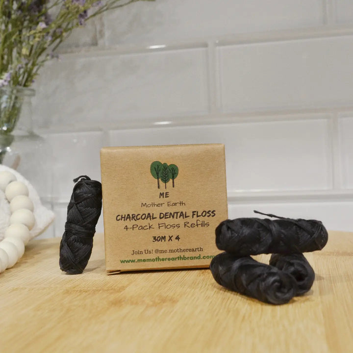 Box of Mother Earth Charcoal Dental Floss Refills with black dental floss on a wooden surface.